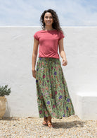 Woman wears floral print cotton skirt with wide elastic waistband, paired with a wide neck mod top rose pink
