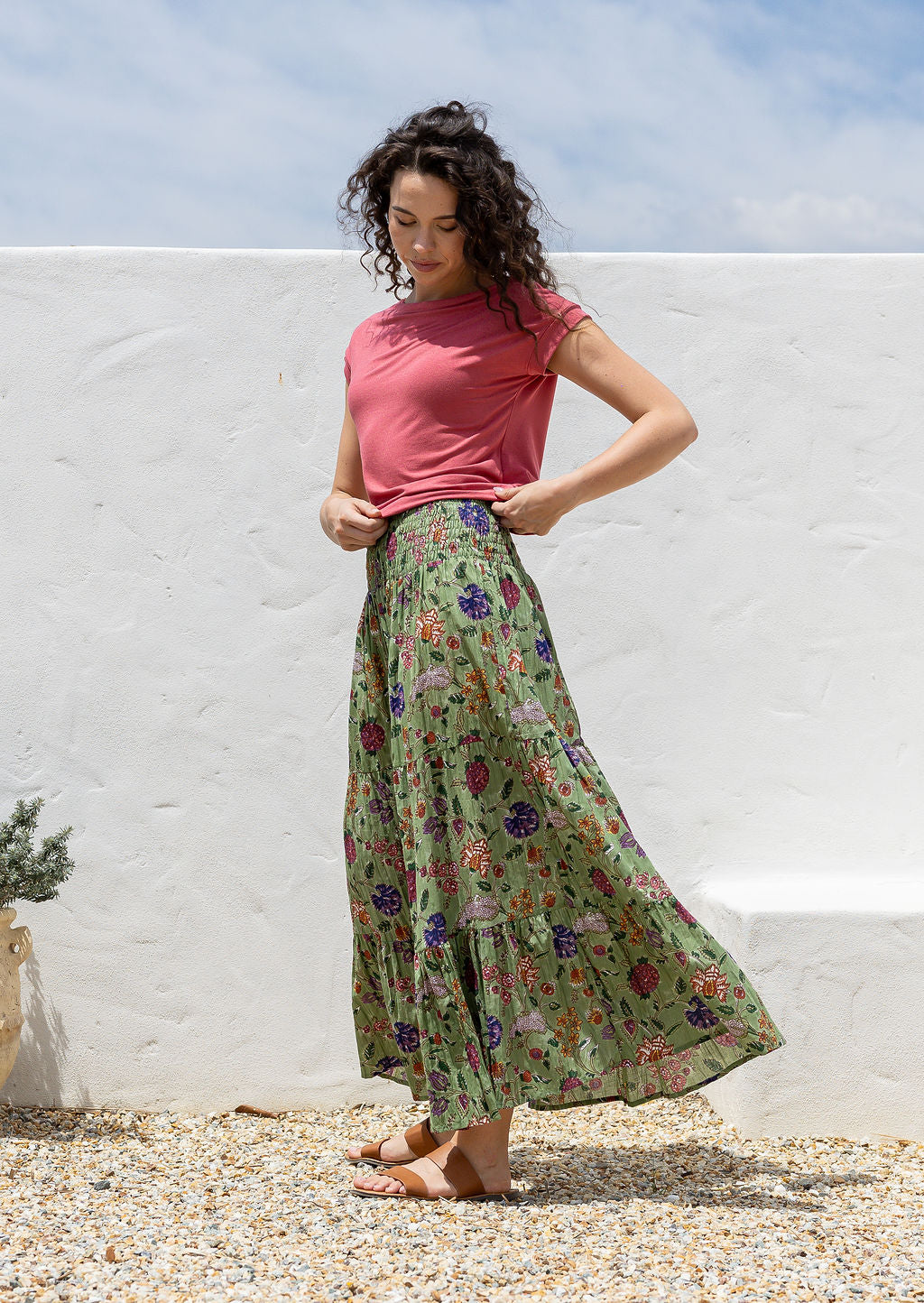 Woman posing sideways wearing a beautiful floral printed cotton skirt with tiers and wide shirred waistband.