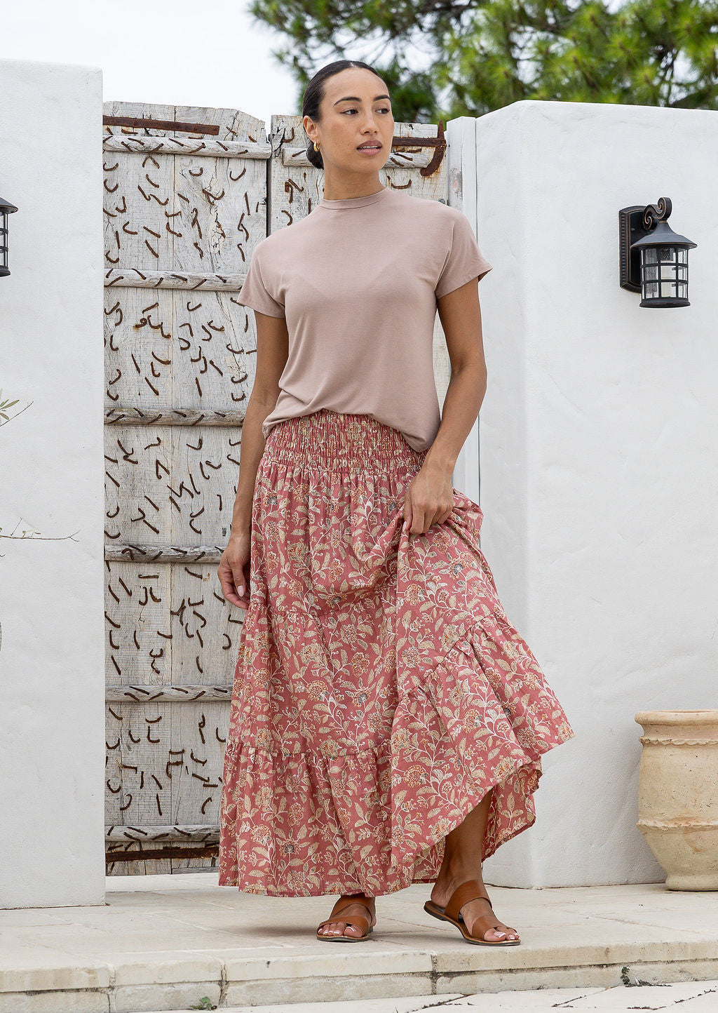 Model is wearing 100% cotton tiered maxi skirt in rose pink based floral print with wide elasticated waistband.