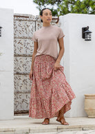Model is wearing 100% cotton tiered maxi skirt in rose pink based floral print with wide elasticated waistband.