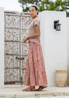 Model standing sideways wearing a three tiered, cotton maxi skirt with plain basic top