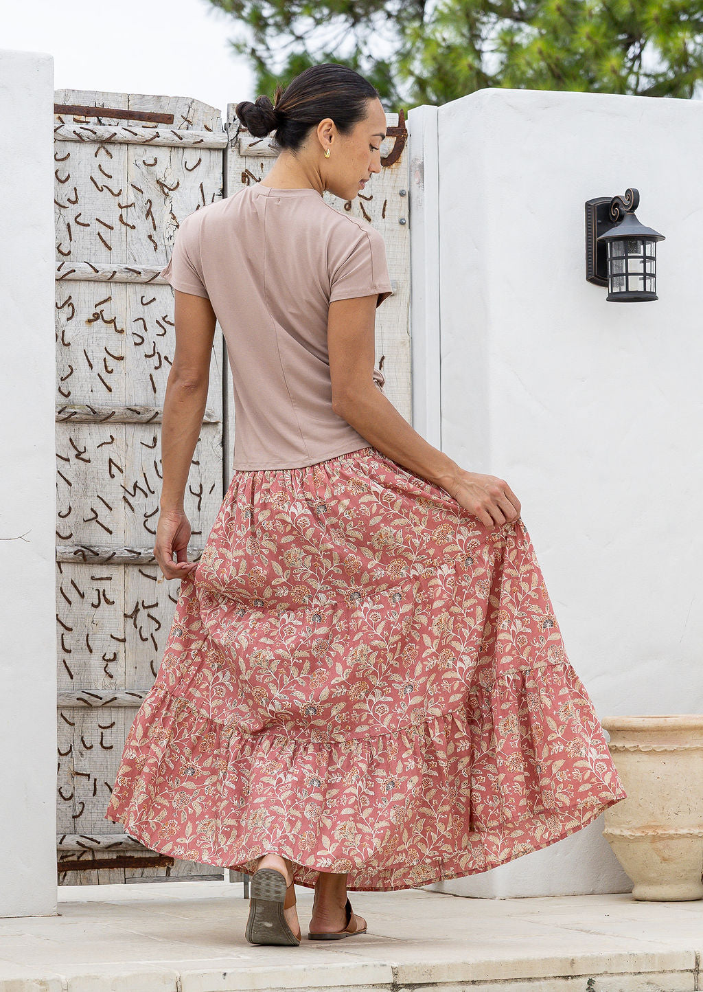Model standing backwards wearing a three tiered, cotton maxi skirt with plain basic top