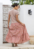 Model standing backwards wearing a three tiered, cotton maxi skirt with plain basic top