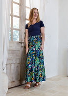 Model standing sideways wearing a three tiered, cotton maxi skirt with plain basic top