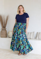 Model standing sideways wearing a three tiered, cotton maxi skirt with plain basic top