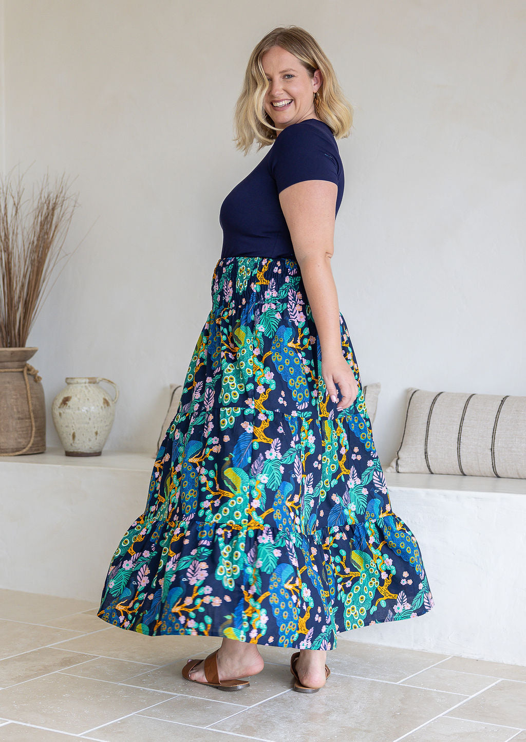 Model standing sideways wearing a three tiered, cotton maxi skirt with plain basic top
