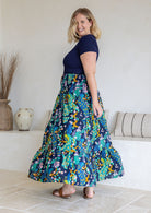 Model standing sideways wearing a three tiered, cotton maxi skirt with plain basic top