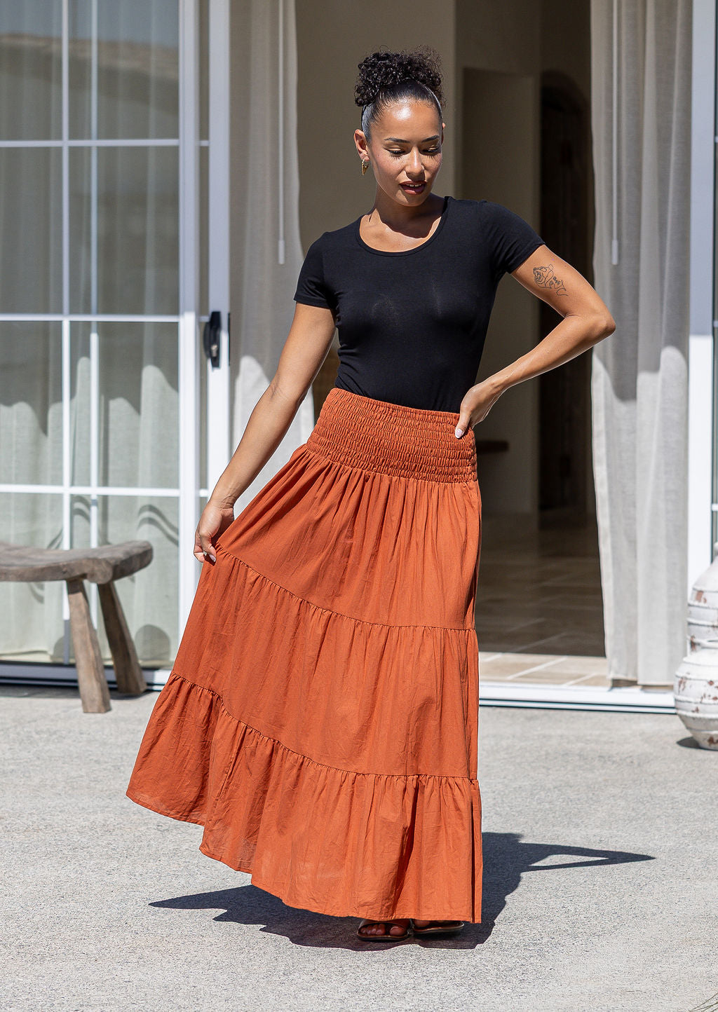 Woman wearing a black stretch top and rust-coloured cotton maxi skirt with a ruched waistband