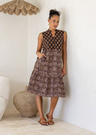 Woman wearing a brown Indian Cotton patterned dress  with her hand in a pocket in a living room setting