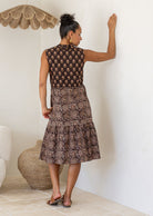 Rear view of Woman wearing a patterned dress in a room with a textured wall and woven basket.