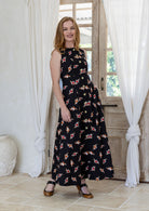 Woman wearing a sleeveless cotton black based floral dress paired with tan heels