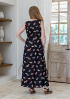 Back view of a woman wearing a sleeveless cotton maxi dress with small floral clusters on a black base