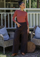 Woman in pink top and brown cotton corduroy wide leg pants with one hand in pockets