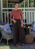 Woman in pink long sleeve top and brown cotton corduroy wide leg pants standing outdoors