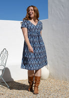 Model wearing a cotton V-neck relaxed fit dress with empire waistline and short sleeves.