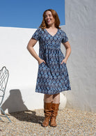 Model wearing a cotton V-neck short sleeve dress with both hand in pockets. 