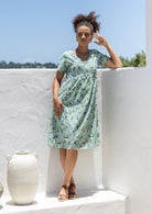 Model wearing a cotton V-neck short sleeve dress with empire waistline and  pocket.