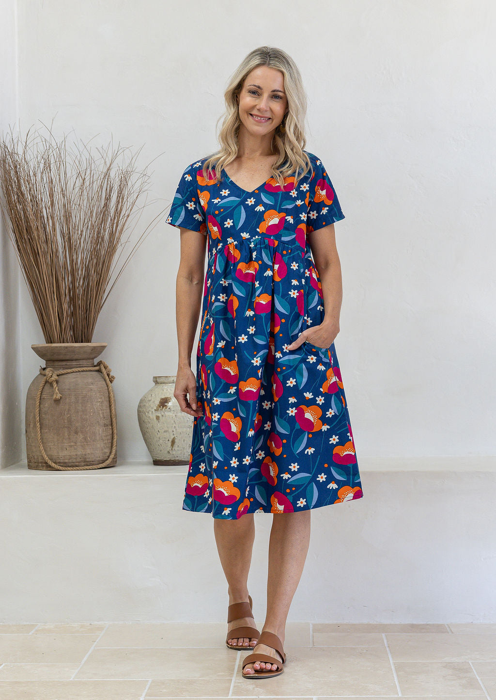 Model wearing a cotton V-neck short sleeve dress with empire waistline and  pocket.