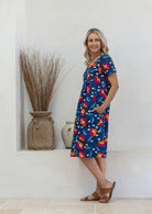 Model stands sideways wearing a cotton V-neck relaxed fit dress with empire waistline and short sleeves.