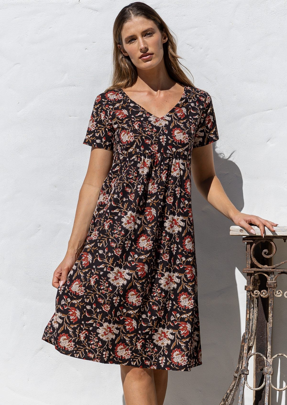 Model poses in a cotton V-neck short sleeve dress with empire waistline and  pocket.