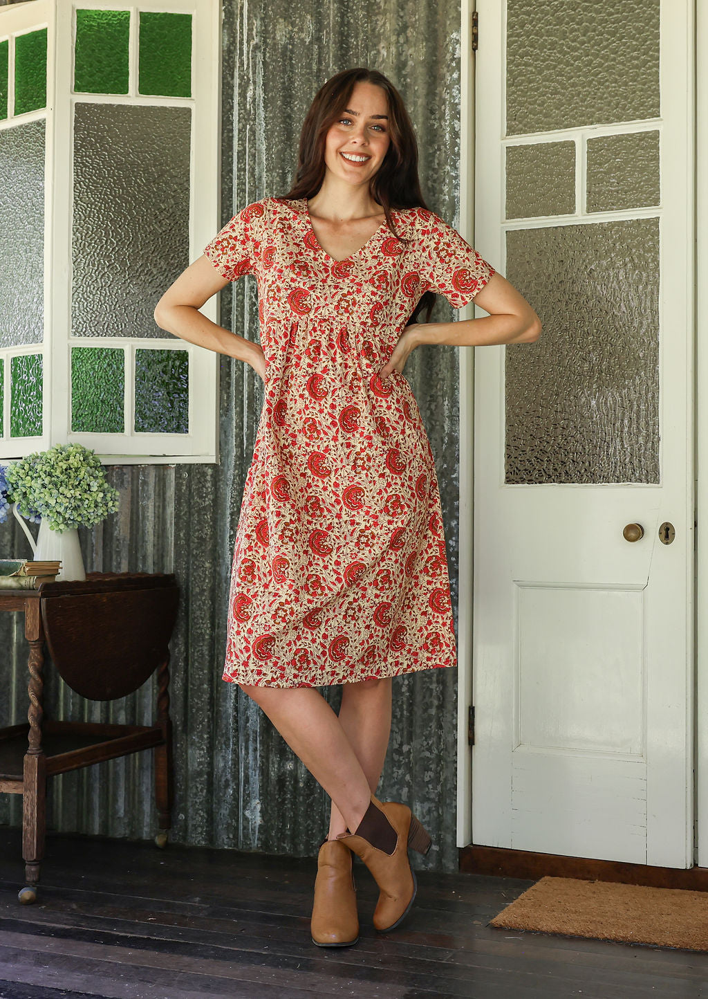 Model wearing a cotton V-neck relaxed fit dress with empire waistline and short sleeves.