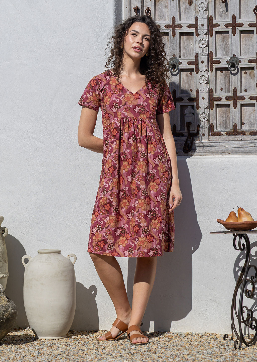 Model wearing a cotton V-neck short sleeve dress with empire waistline and  hand in pocket.