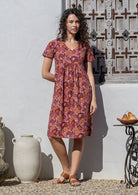 Model wearing a cotton knee length dress with empire waist, short sleeves and pockets.