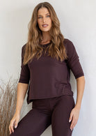 Woman wearing a dark brown rayon jersey relaxed fit top with a drop shoulder and fitted 3/4 sleeves, paired with leggings