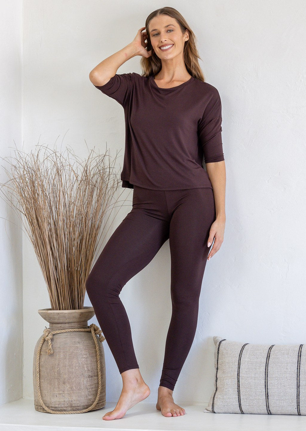 Woman wearing a dark brown rayon jersey relaxed fit top with fitted 3/4 sleeves, paired with dark brown leggings
