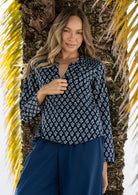 Woman wearing a 100% cotton navy blue top and navy plain pants standing against a palm tree.