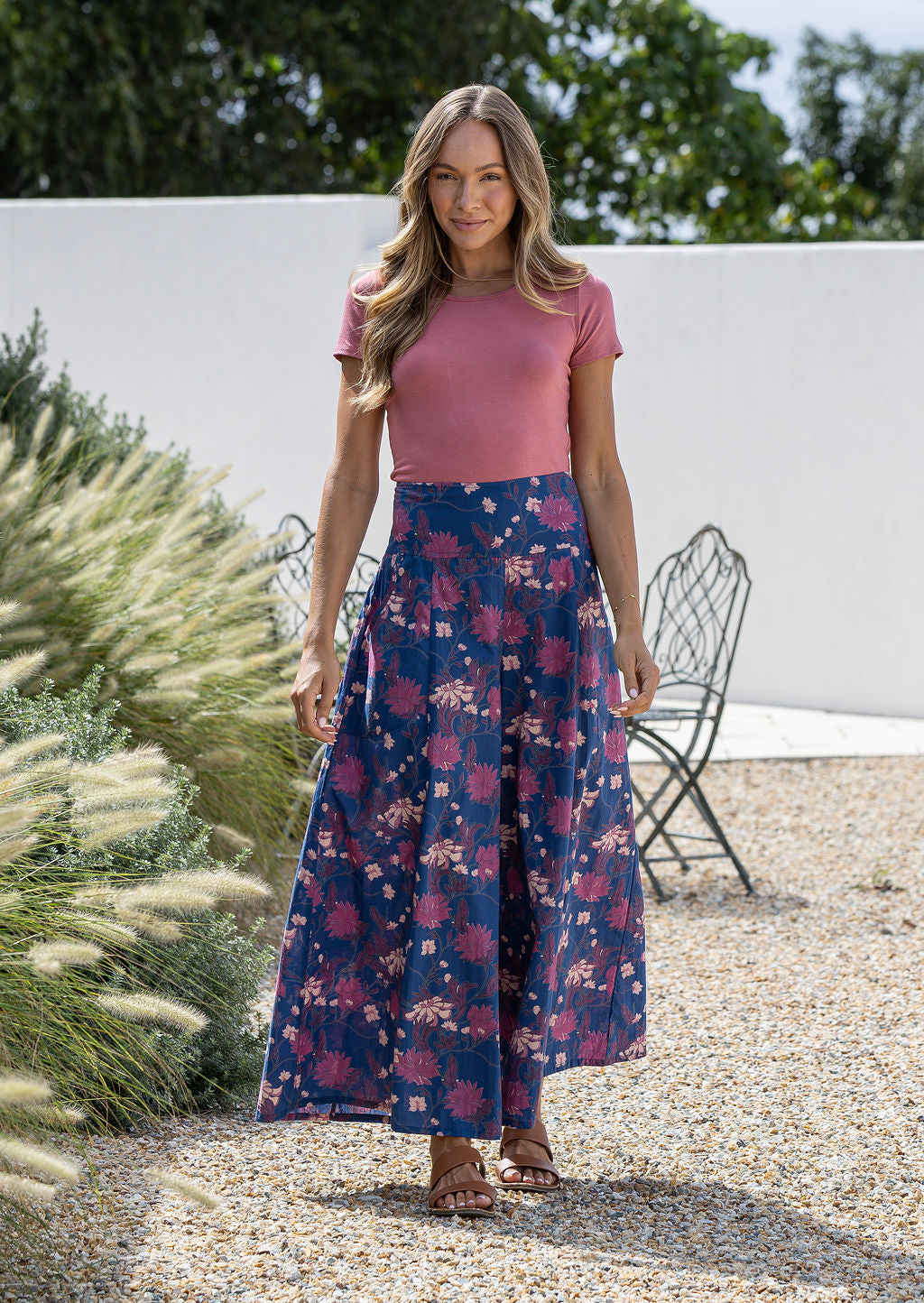 Woman wearing a 100% cotton wide legged navy blue based floral pants standing outdoors.