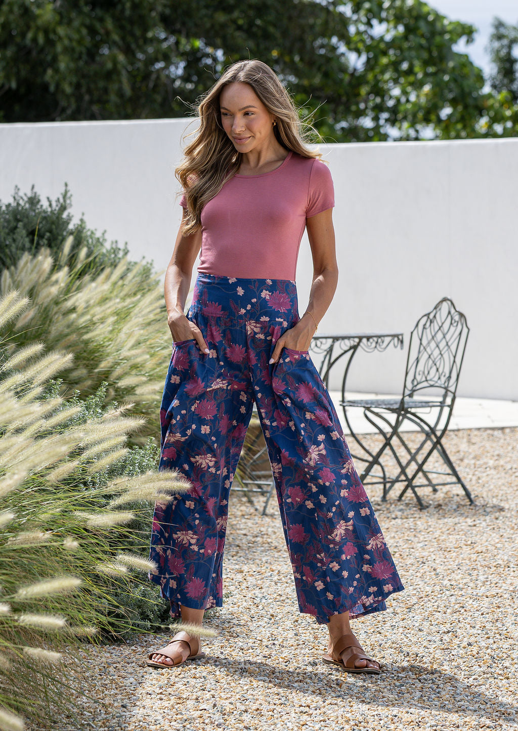 Woman wearing a 100% cotton wide legged navy blue based floral pants with hands in pockets