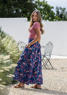 Woman standing sideways wearing a  wide legged navy blue cotton floral pants with hands in pockets