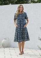 Woman wearing a navy blue based floral print cotton dress with hands in pocket