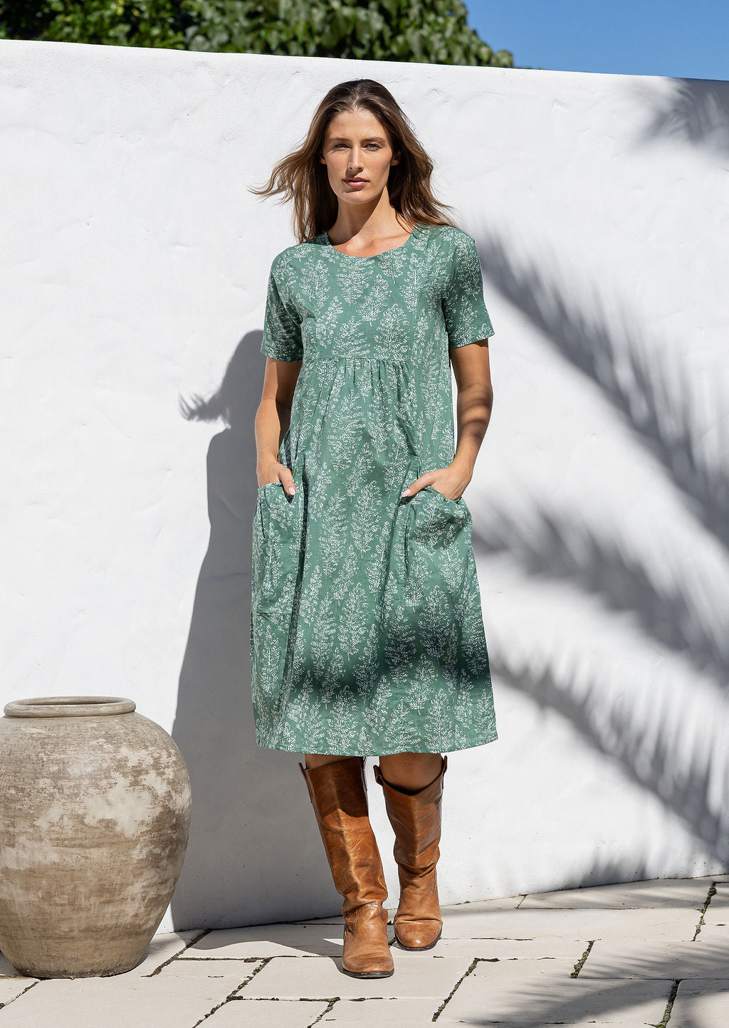 Woman wearing a sage green based floral print cotton dress with hands in pocket