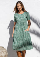 Woman posing in cotton over the knee length relaxed fit sun dress with short sleeves, with her hand in a pocket