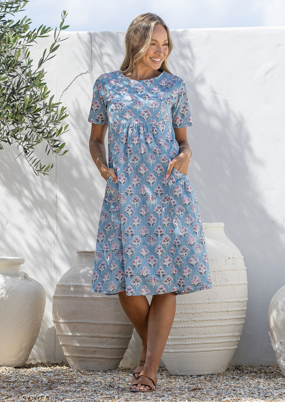 Woman poses in a blue based cotton floral short sleeve dress with round neckline