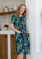 Woman wearing a 100% cotton lightweight lined relaxed fit knee length dress with pin tucks 