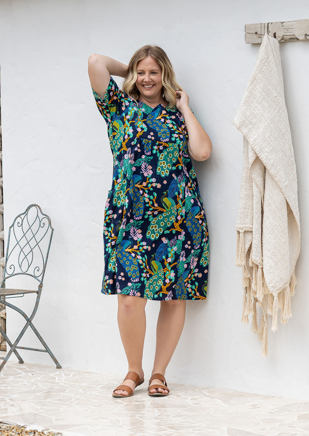 Woman poses in a navy based cotton colourful floral short sleeve dress with round neckline