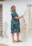 Woman stands sideways wearing a 100% cotton lightweight lined relaxed fit knee length dress 