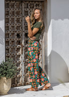 Model stands wearing a 100% cotton printed wide leg cotton pants featuring pleated ankles and pockets