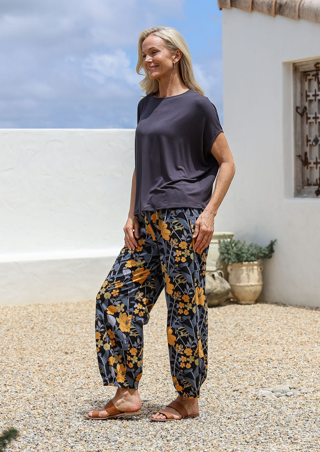 Woman posing in a black based floral wide-leg cotton pants with pockets and pleated ankle