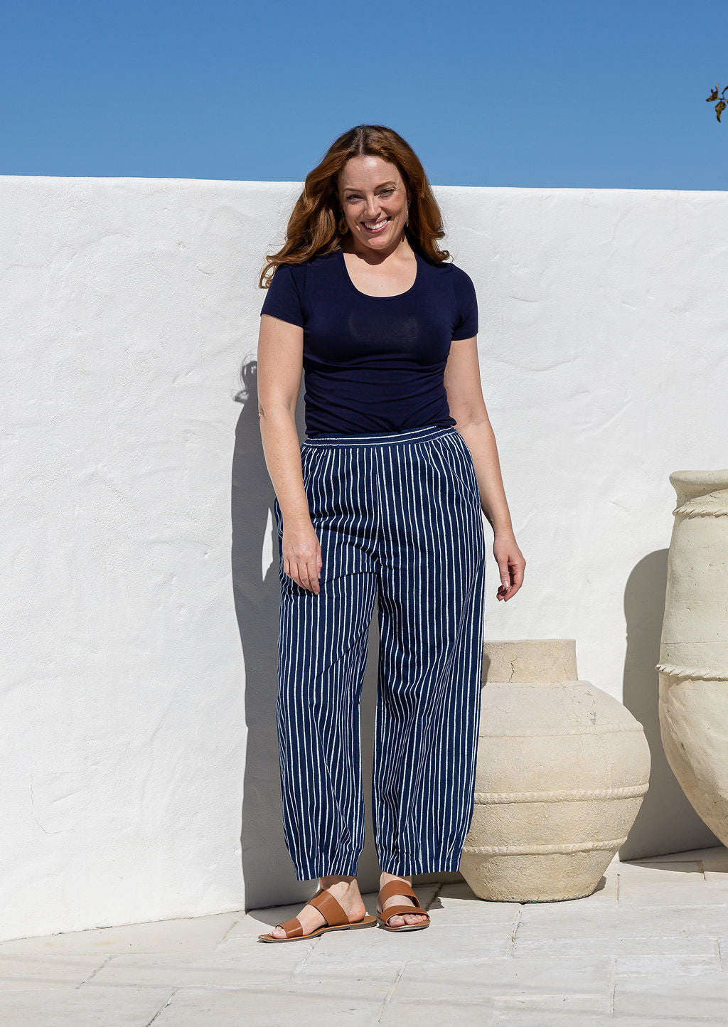 Woman wearing a 100% cotton wide leg pants in navy based white striped print