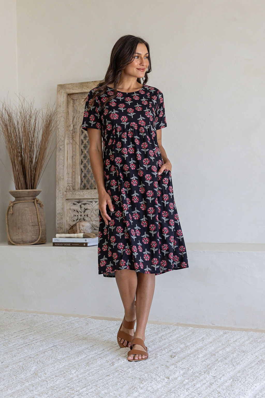 Woman poses in a black based cotton floral short sleeve dress with round neckline