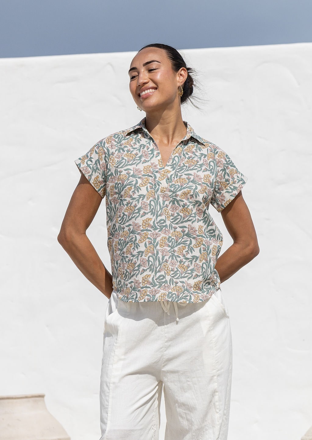 Woman poses in relaxed fit cotton short sleeve top with rolled cuffs sleeves, collar and V neckline.