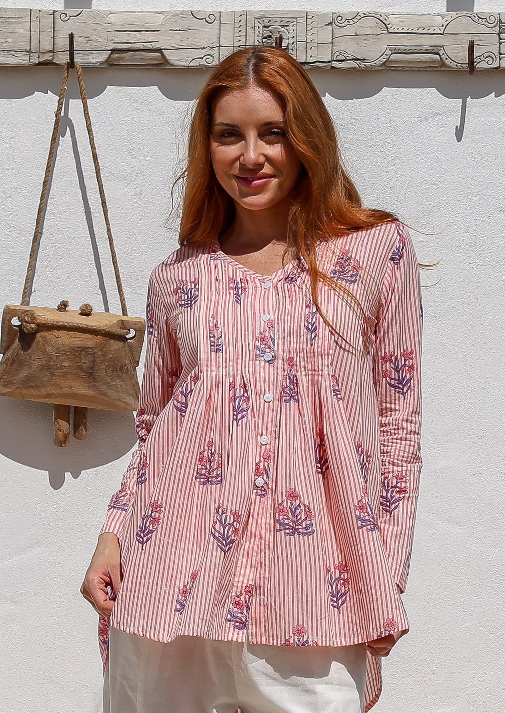 Woman wearing a 100% cotton Pink striped floral long-sleeve blouse with pleated front. 
