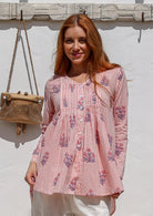 Woman wearing a 100% cotton Pink striped floral long-sleeve blouse with pleated front. 