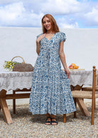 Blue and white floral print tiered maxi dress with cap sleeves and V-neck, worn by model outdoors