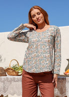Model wearing 100% cotton long sleeve top with round neckline and tiny pleat detail from the center of the neckline.
