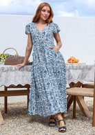 Blue and white floral print maxi dress with short sleeves and V-neck, worn by model standing outdoors.